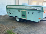 Custom light blue pop-up RV rental with nature decals: tree, bear, moon, stars, and forest scene.