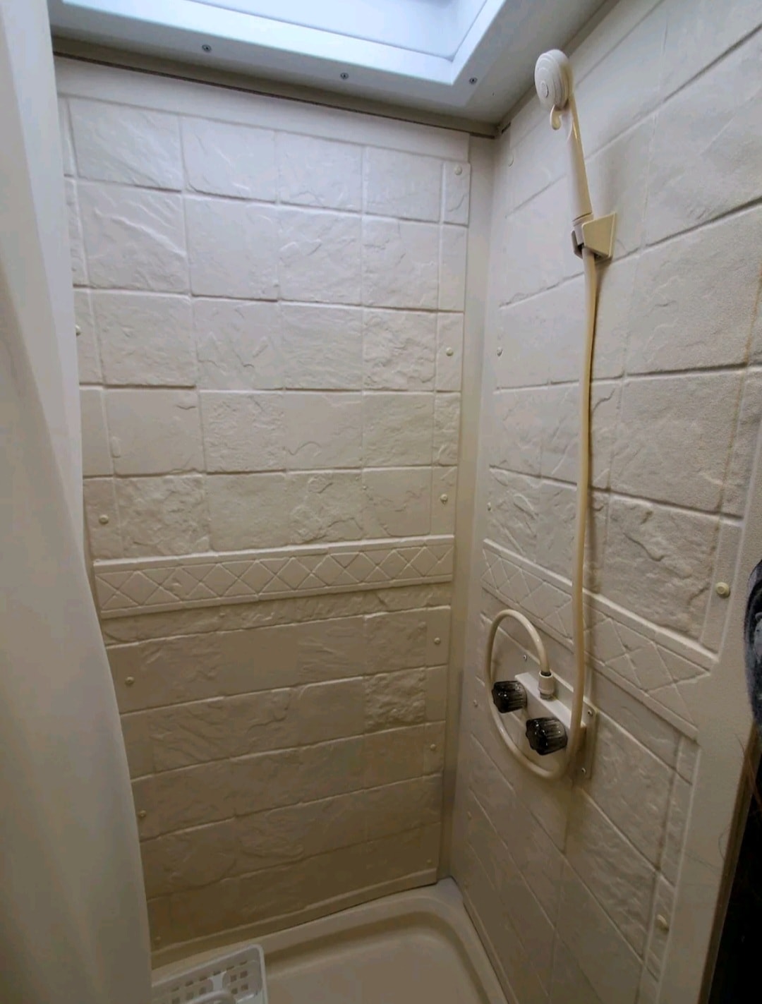 Compact RV rental shower with textured walls and handheld showerhead. Ideal for road trips. — photo 6