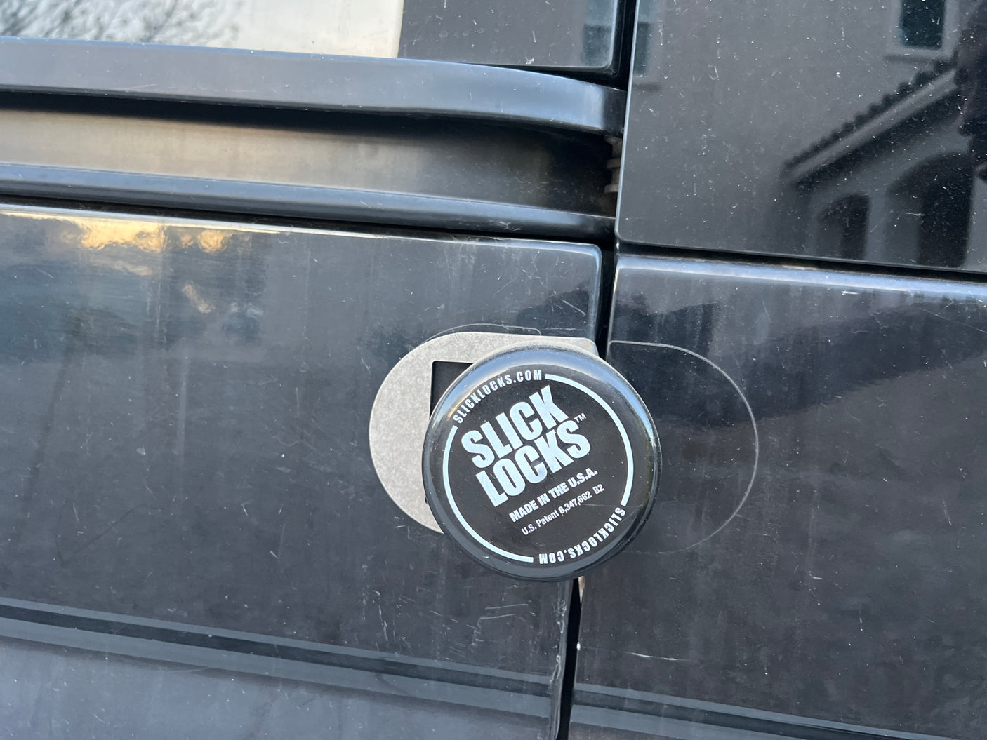 A black Slick Locks disc lock secures an RV rental door, enhancing vehicle security.