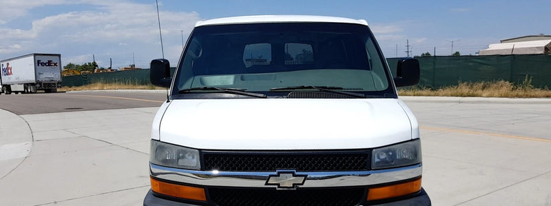 White cargo van, ideal for RV rental, parked on asphalt. A FedEx truck and green fence are in the background. — photo 1
