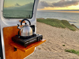 RV rental perks: Kettle on a portable stove, ready for hot drinks with a beautiful ocean view from the camper.