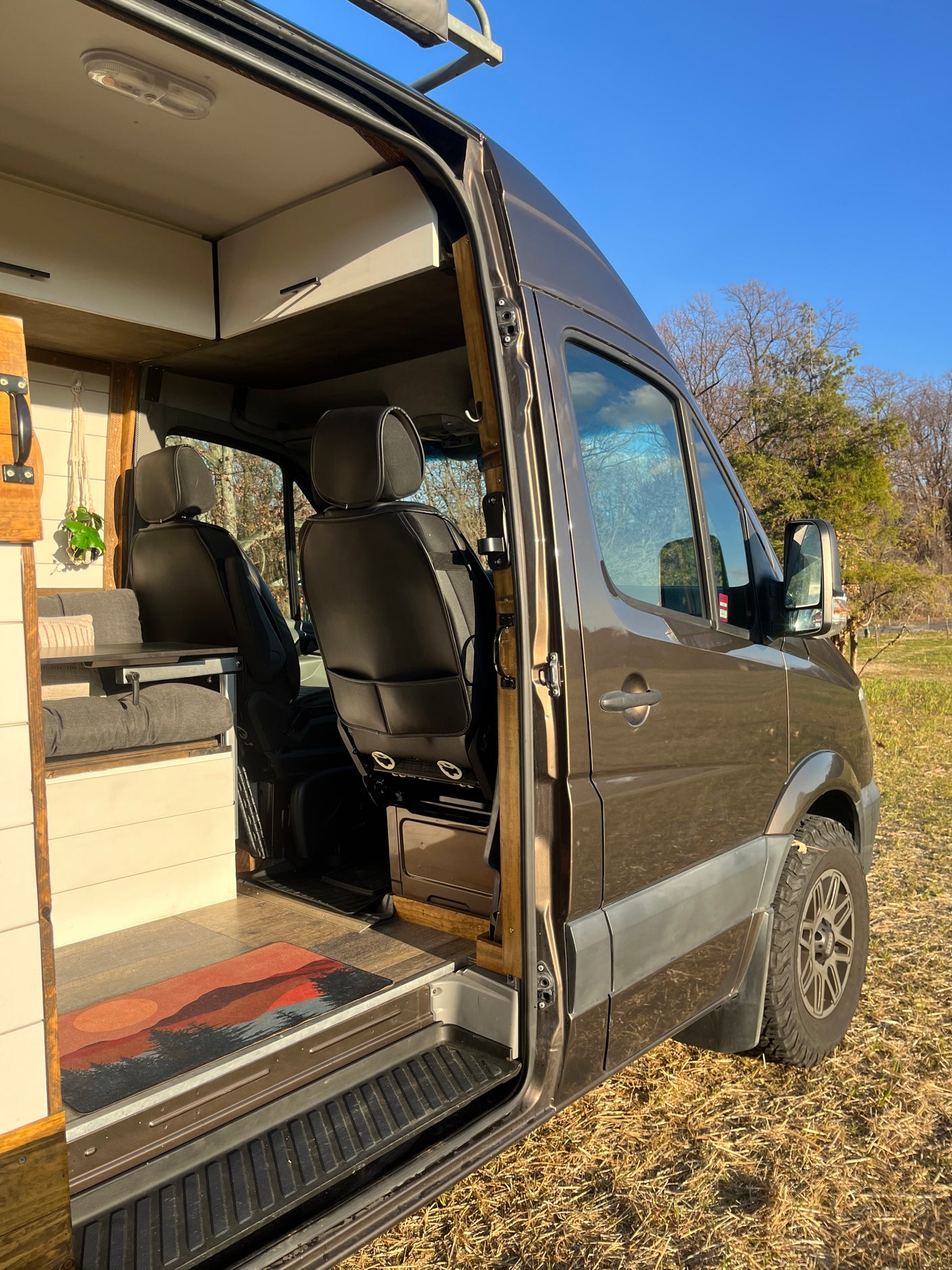 Step inside this modern RV rental camper van, revealing its custom-built interior with seating and practical storage solutions.