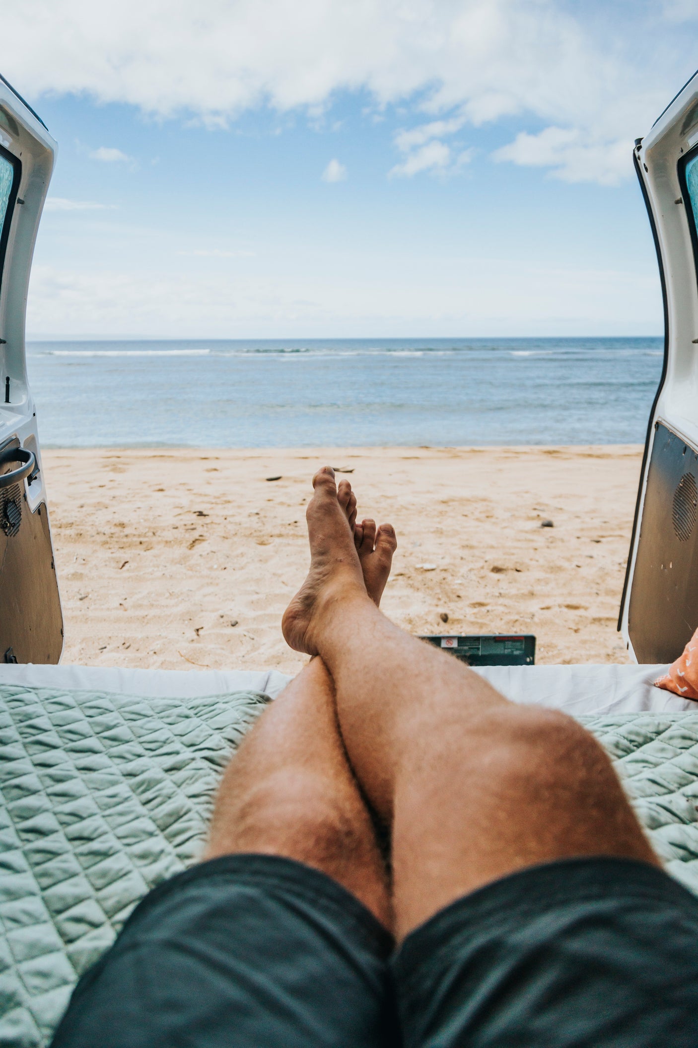 Enjoying ocean views from a comfortable RV rental. Legs crossed, looking out at the beach and sea from inside.