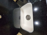 Functional RV rental kitchen area: white sink, black speckled countertop, and overhead light reflections.