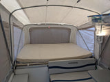 Inside a spacious RV rental, a pop-up camper with a large bed, seating, and overhead storage for camping comfort.