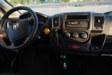 Driver's view inside an RV rental, showing the steering wheel, dashboard, radio, climate controls, and a 3.7m/12ft height warning.