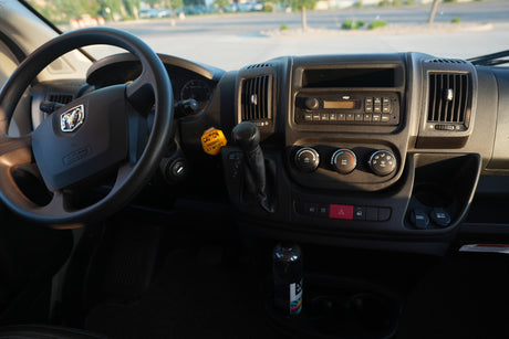 Driver's view inside an RV rental, showing the steering wheel, dashboard, radio, climate controls, and a 3.7m/12ft height warning.