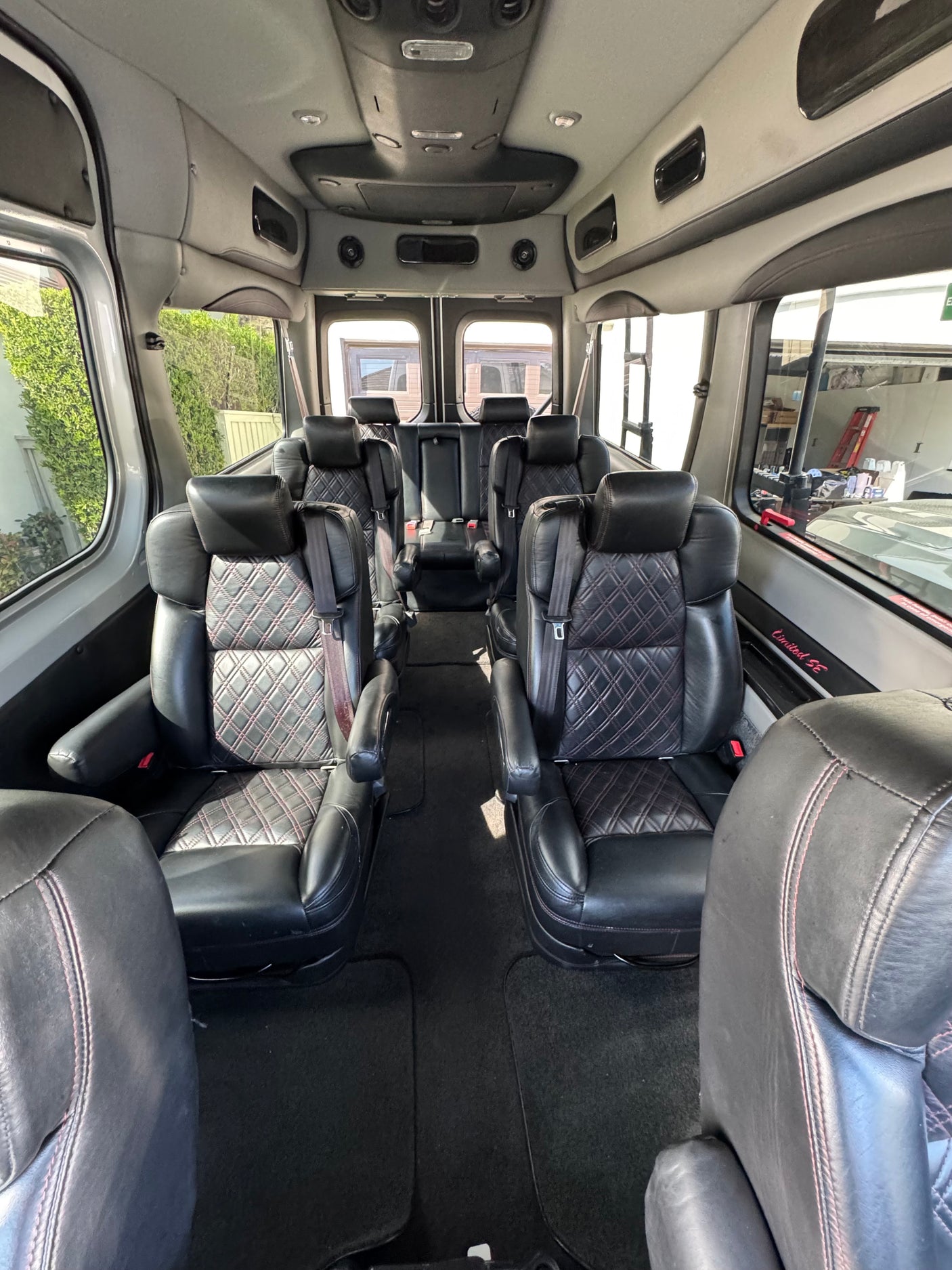 Spacious luxury RV rental interior with black leather captain's chairs featuring diamond stitching, ideal for comfortable group travel.