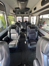 Spacious luxury RV rental interior with black leather captain's chairs featuring diamond stitching, ideal for comfortable group travel.