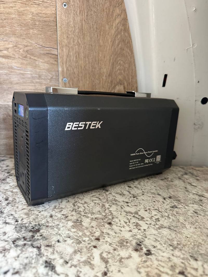 A black BESTEK 1000W pure sine wave power inverter for an rv rental, offering portable power. It sits on a speckled counter. — photo 20