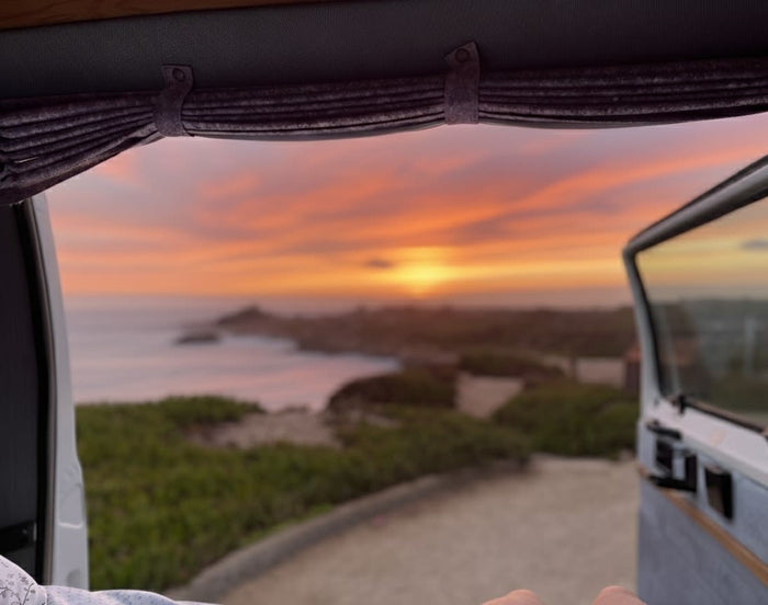 Unforgettable coastal sunset from an RV rental, viewed from inside the van with an open side door. Perfect for travel.
