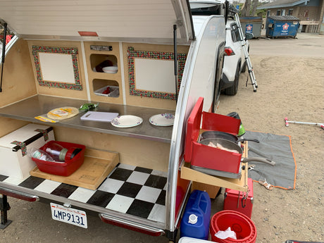 Enjoying outdoor cooking with this RV rental! Teardrop trailer galley shows bacon on the stove & counter space.