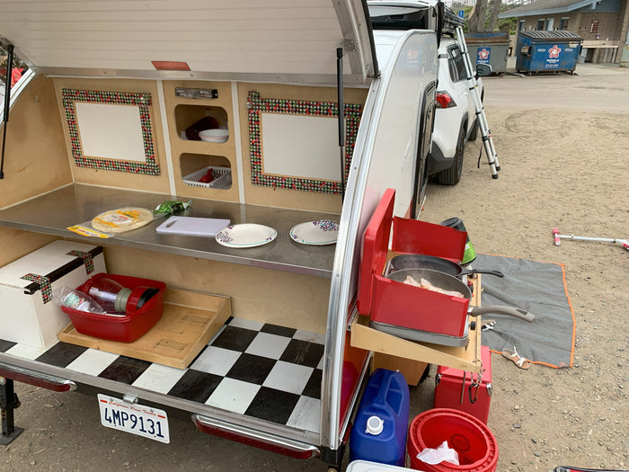 Enjoying outdoor cooking with this RV rental! Teardrop trailer galley shows bacon on the stove & counter space.