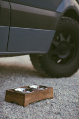 Pet bowls on gravel by an RV rental van, ready for a pet-friendly road trip adventure.