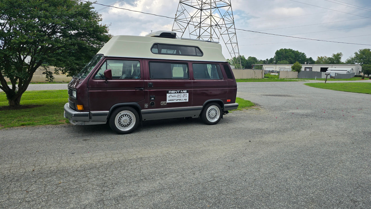 Maroon VW T3 pop-top camper van, a perfect RV rental option. Parked on asphalt with distinctive multi-spoke wheels.