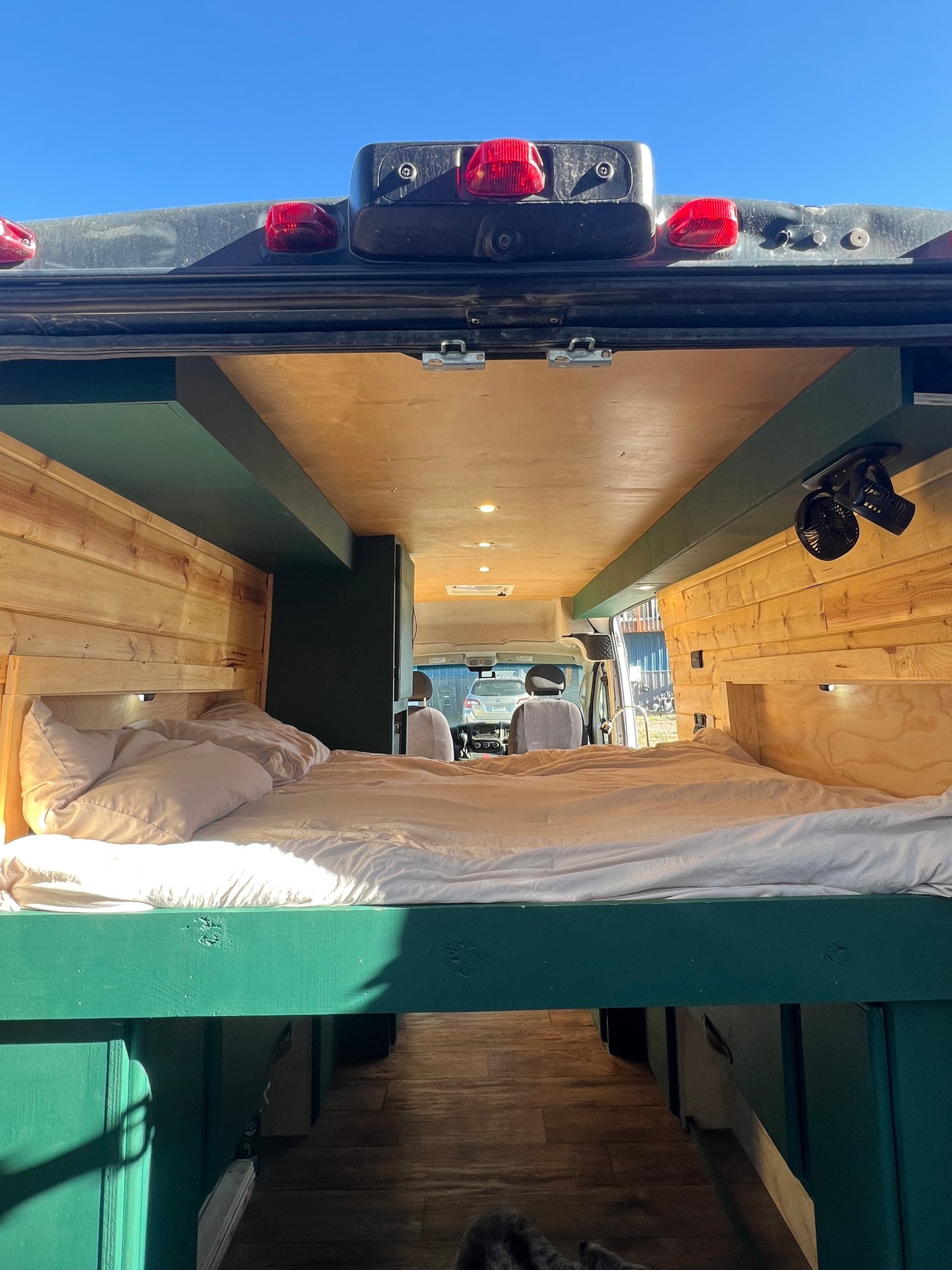 Cozy RV rental interior with a comfortable bed, wood paneling, and a view to the front cabin. Perfect for mobile adventures.