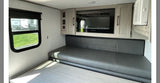 RV rental interior featuring a dark gray seating area, convertible table, built-in TV, and overhead storage.