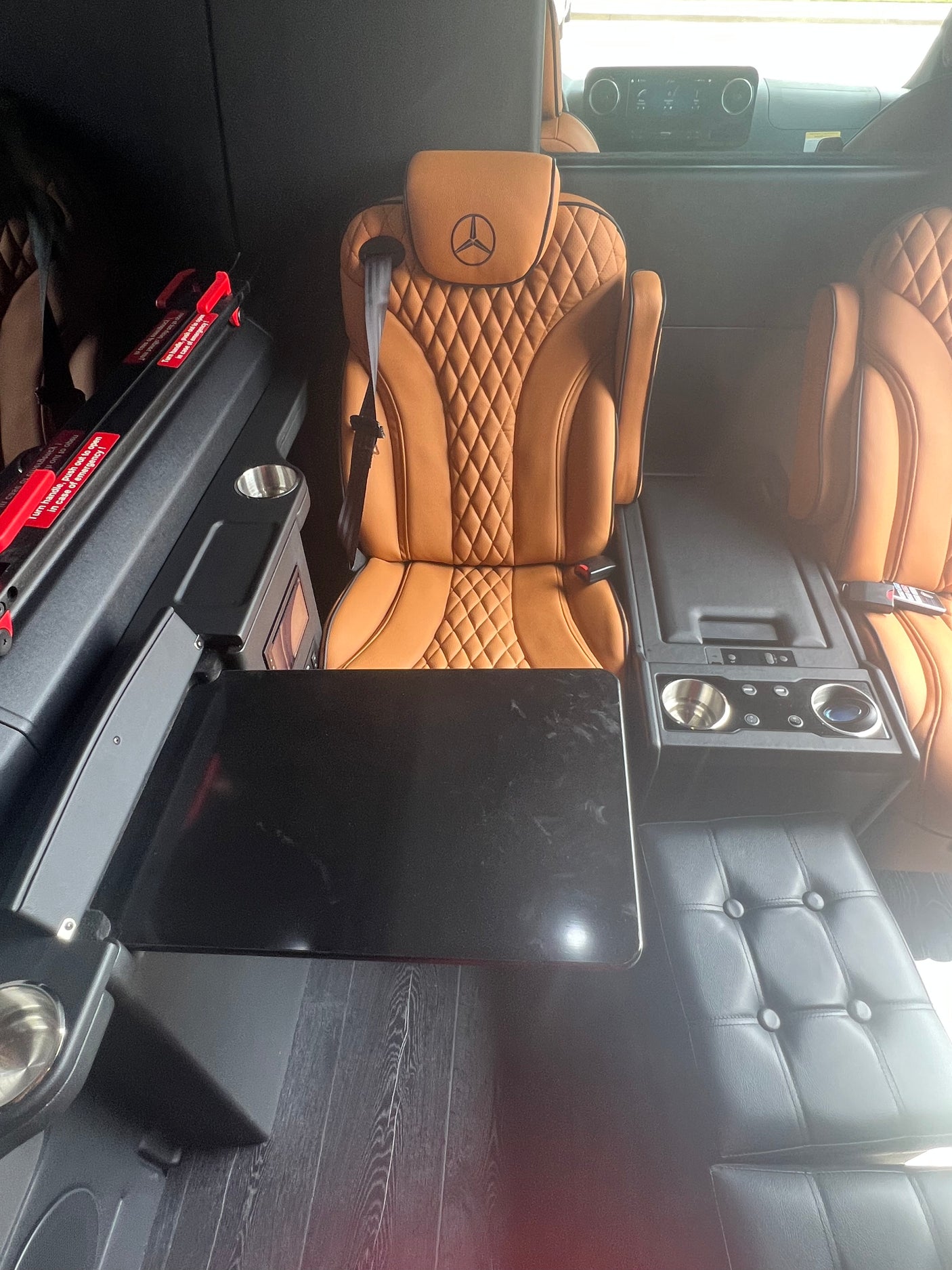 Luxury RV rental interior with plush Mercedes-Benz leather seats, a deployable table, and integrated amenities for premium travel.