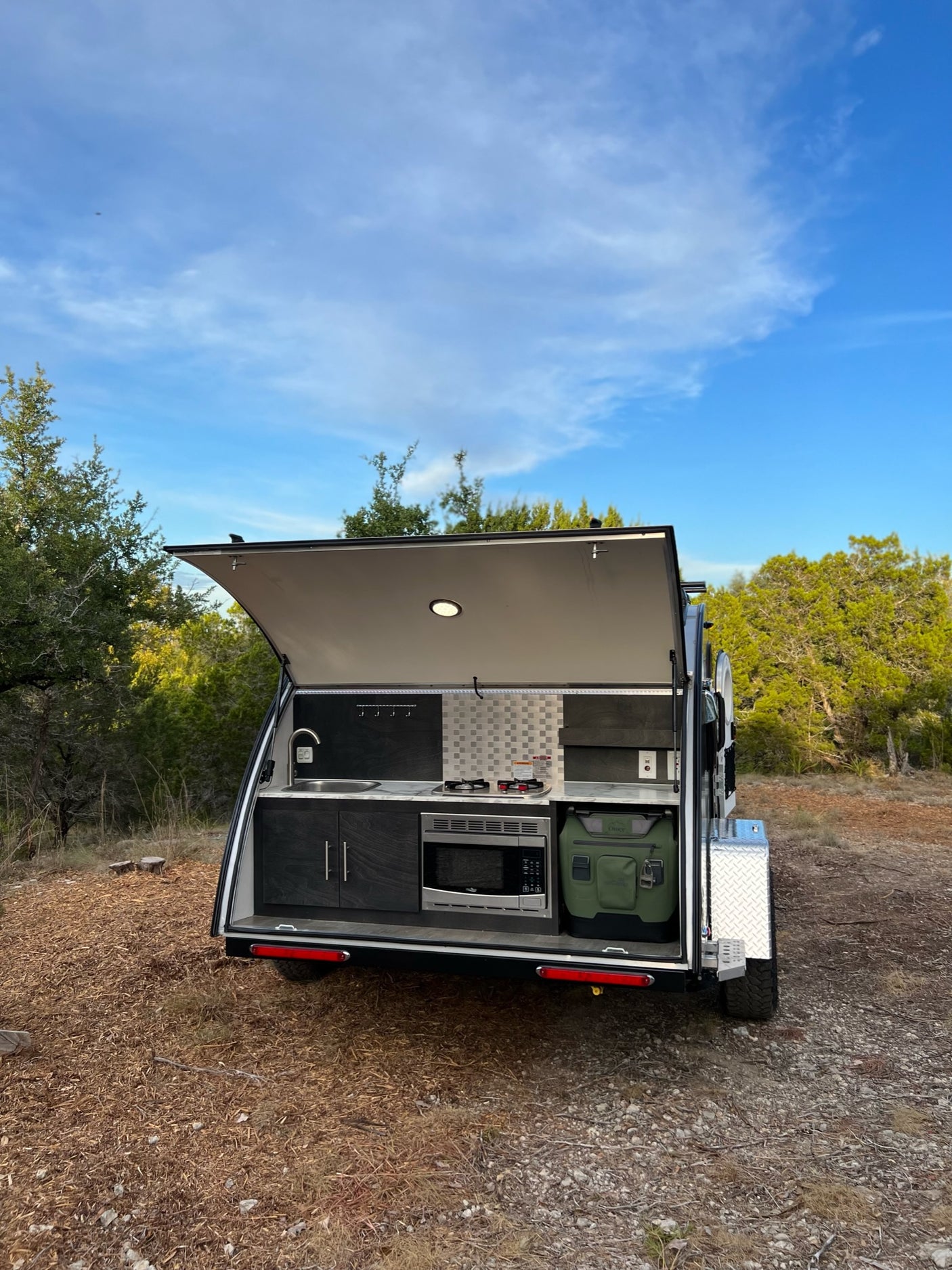 RV rental: Modern teardrop trailer featuring a well-appointed outdoor kitchen, perfect for camping adventures.