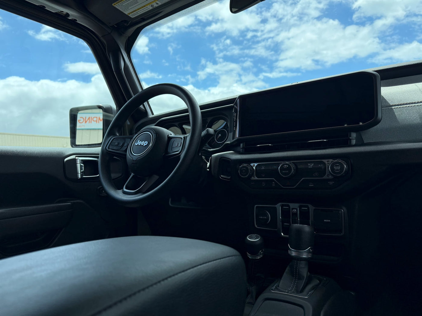  and gear shifters. Blue sky and clouds visible through windshield.|Green Jeep Gladiator pickup with rooftop tent — photo 4