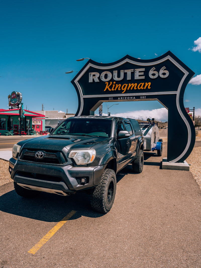 A truck with a camper trailer beneath the iconic Route 66 Kingman sign. Perfect for an RV rental road trip! — photo 11