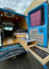 RV rental-ready blue camper van interior featuring a pull-out kitchen, bed, and stylish wood-paneled walls.