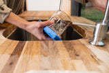 Hands wash a glass in a compact RV rental kitchen sink. Enjoy convenient amenities on your next adventure!