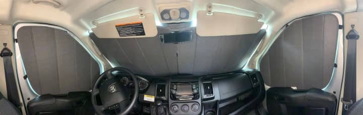 Inside an RV rental: driver's cockpit with full grey insulated window shades for privacy.