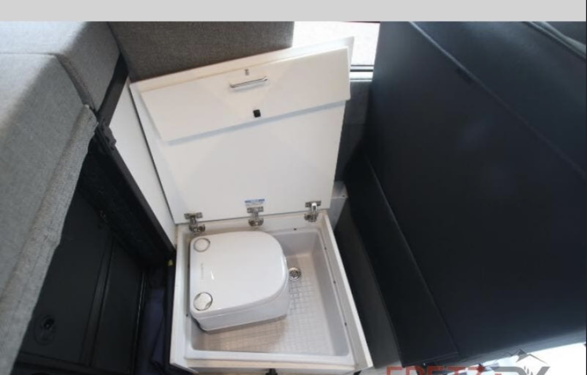 Hidden portable toilet inside a space-saving pull-out compartment, a convenient feature for an RV rental.