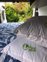 RV rental interior: cozy bed with Planet Pillow & a lush green view from open doors.