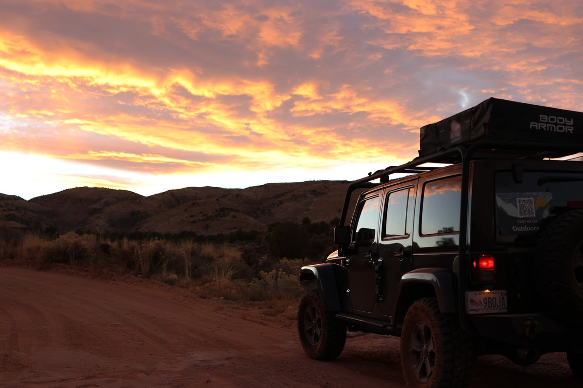  parked roadside against towering red rock formations under blue sky.|Off-grid camping with a custom "RV rental" alternative: Jeep