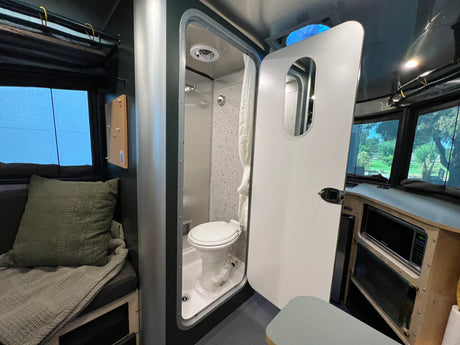Explore this RV rental's clever interior: wet bath with toilet & shower, functional kitchen, and cozy seating area.