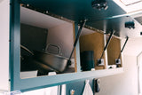 Spacious overhead storage in an RV rental, featuring open cabinets with gas struts, a pot, and kitchen essentials.