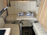 RV rental's inviting dining space with cream bench seating & adjustable table set for two. Ideal for journeys.