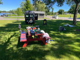 Family enjoying a sunny day outdoors with their RV rental (Mercedes Sprinter van) at a park, featuring a picnic table and kids playing.