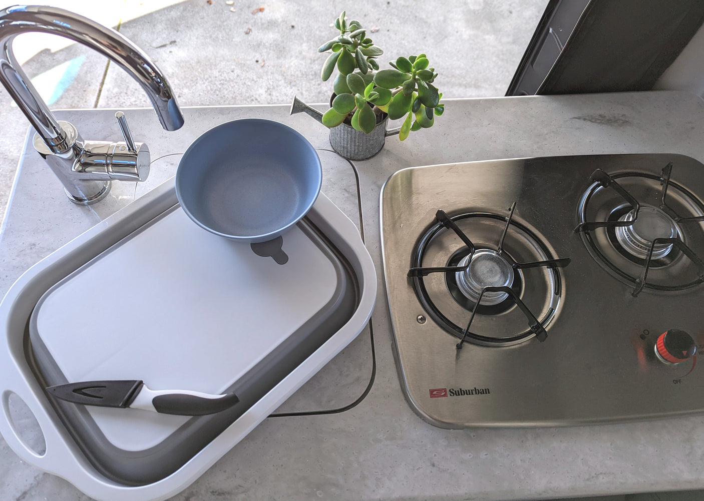 Experience our RV rental kitchen, featuring a full sink, Suburban stove, and space-saving basin.