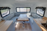 RV rental: Light-filled interior with U-shaped dinette, adjustable wood table, and compact kitchen area.