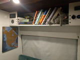 RV rental interior showing a well-organized overhead shelf with books, board games, and controls. Adventure awaits!