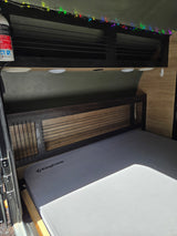 RV rental: KingCamp mattress, slatted headboard, overhead storage with colorful string lights & First Alert extinguisher.