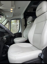 Bright Roadtrek RV rental front cabin with clean white seats & steering wheel. Experience comfort on your next adventure.