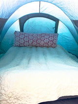 Spacious tent interior with a quilted mattress & floral pillow, ensuring comfort for your RV rental getaway.