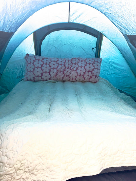 Spacious tent interior with a quilted mattress & floral pillow, ensuring comfort for your RV rental getaway.