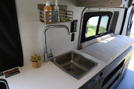Compact RV rental kitchen with sink, faucet, and storage, ideal for road trips and small space living.