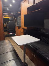 Spacious RV rental interior with a cozy dining area, black leather benches, a table, and a mounted TV.