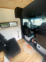 Cozy RV rental interior: wood & white accents, custom van conversion with comfortable seating and a compact window. Ready for adventure!