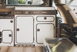 Explore a vintage Westfalia RV rental interior: compact kitchen, storage, and controls, perfect for road trip adventures.
