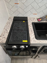 This RV rental kitchen features a gas stove with a glass cover, microwave, and sink, displaying important safety warnings.