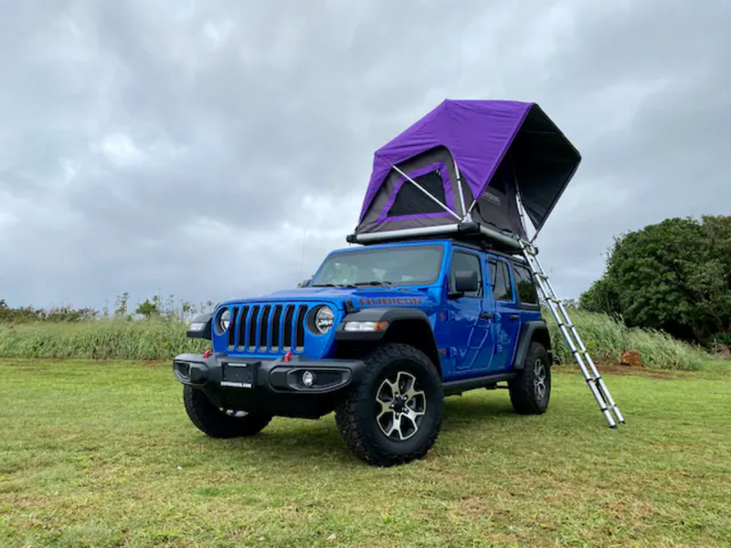 Bright blue Jeep Wrangler with a vibrant purple rooftop tent and ladder, set up on grass. Your RV rental for off-road adventures. — photo 2