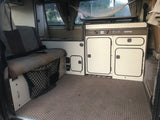 View inside a Westfalia camper rv rental: kitchen unit, rear seat (converts to bed), and ample storage options.