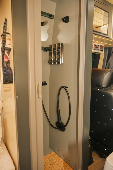 Compact shower with essential amenities like wall-mounted dispensers and a handheld shower in an RV rental.
